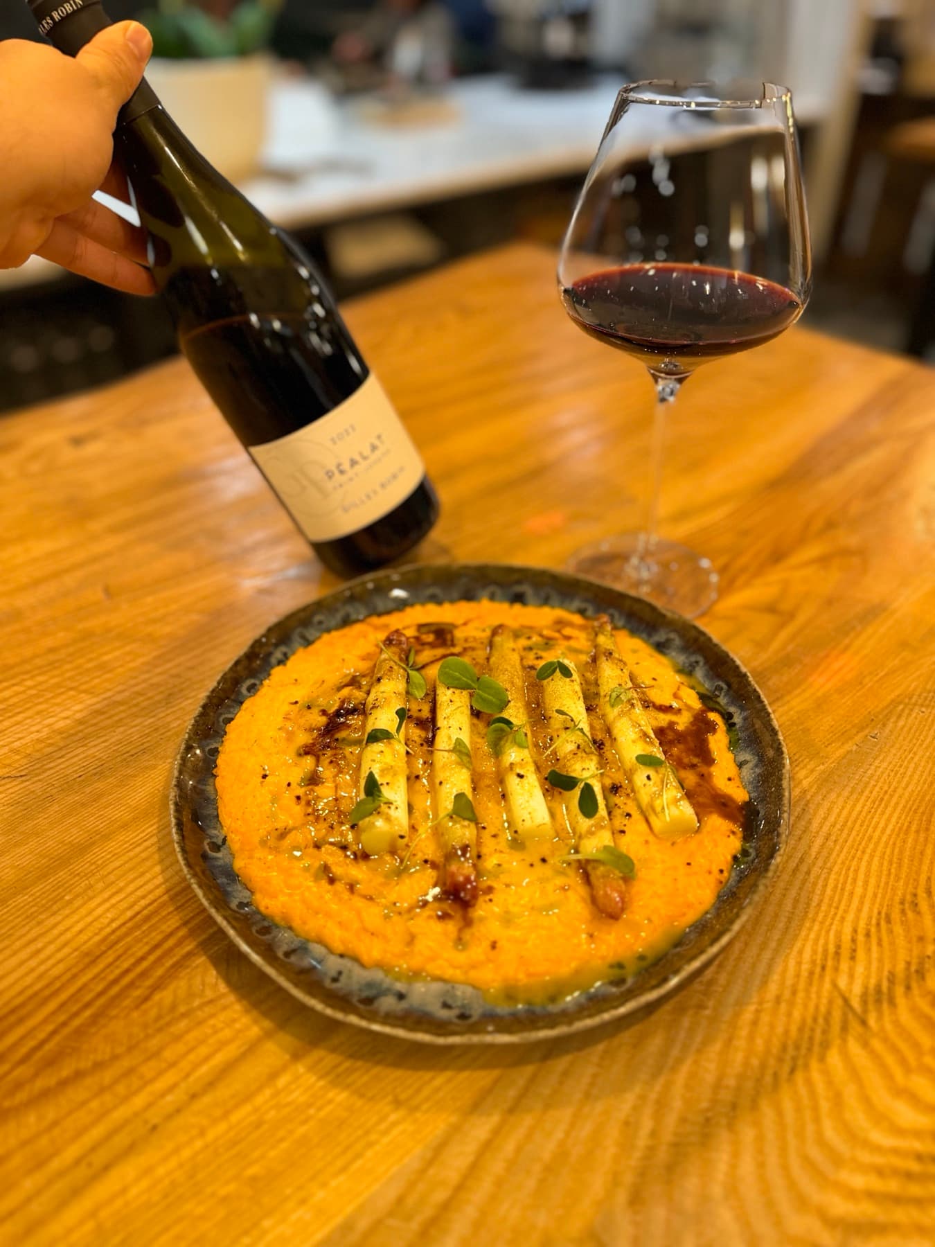 Plat maison servi avec des asperges blanches et un verre de vin